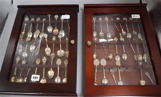 A collection of 48 souvenir spoons, plated, enamelled, etc. in two glazed display cases